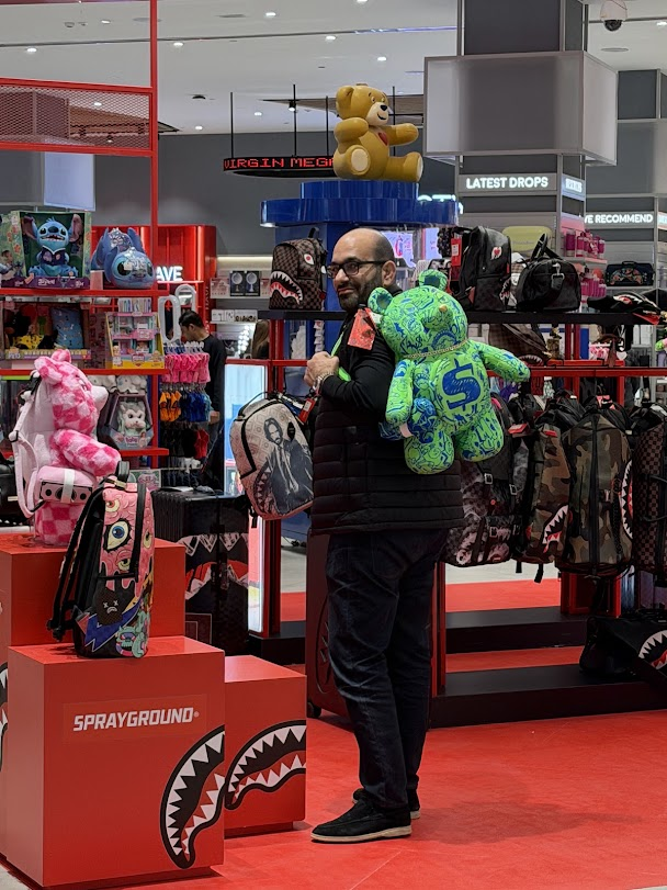 Original photograph of Mazen in a shop carrying the green bear backpack